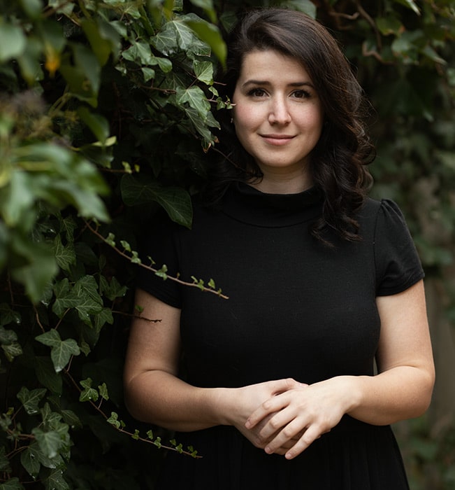 Person standing among green foliage.